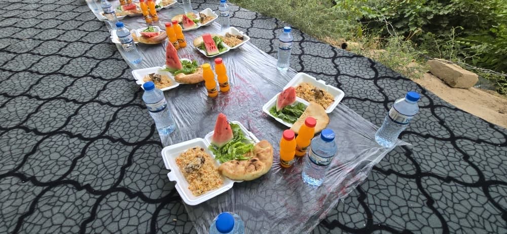 Aşure ikramı öncesi hazırlanan yer sofrası; naan ekmekleri ve ikramlar dizili